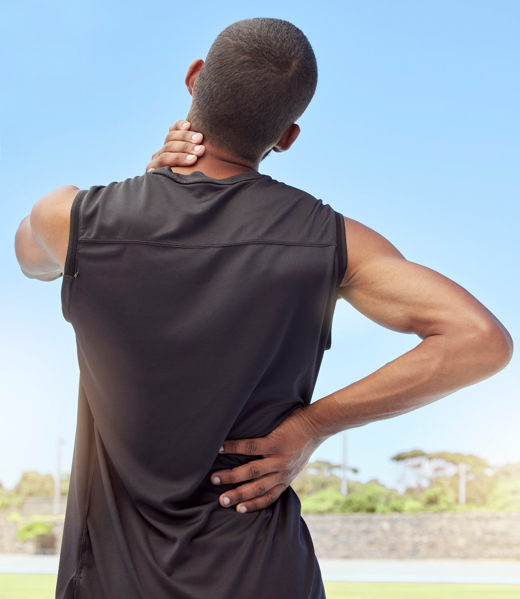 Injured Athlete with Sore Neck and Back Muscles from behind. Unc